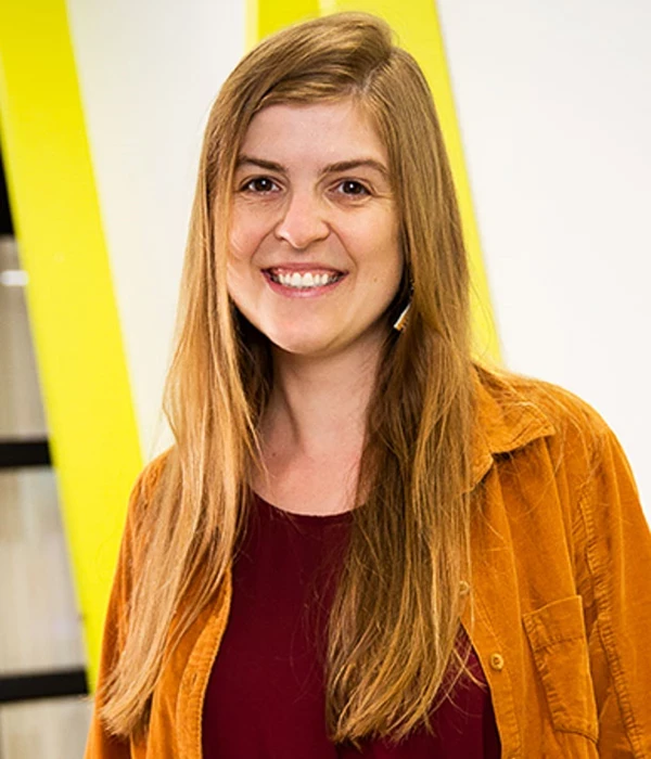 Photo of Ute, smiling at the camera wearing and orange shirt over and red top
