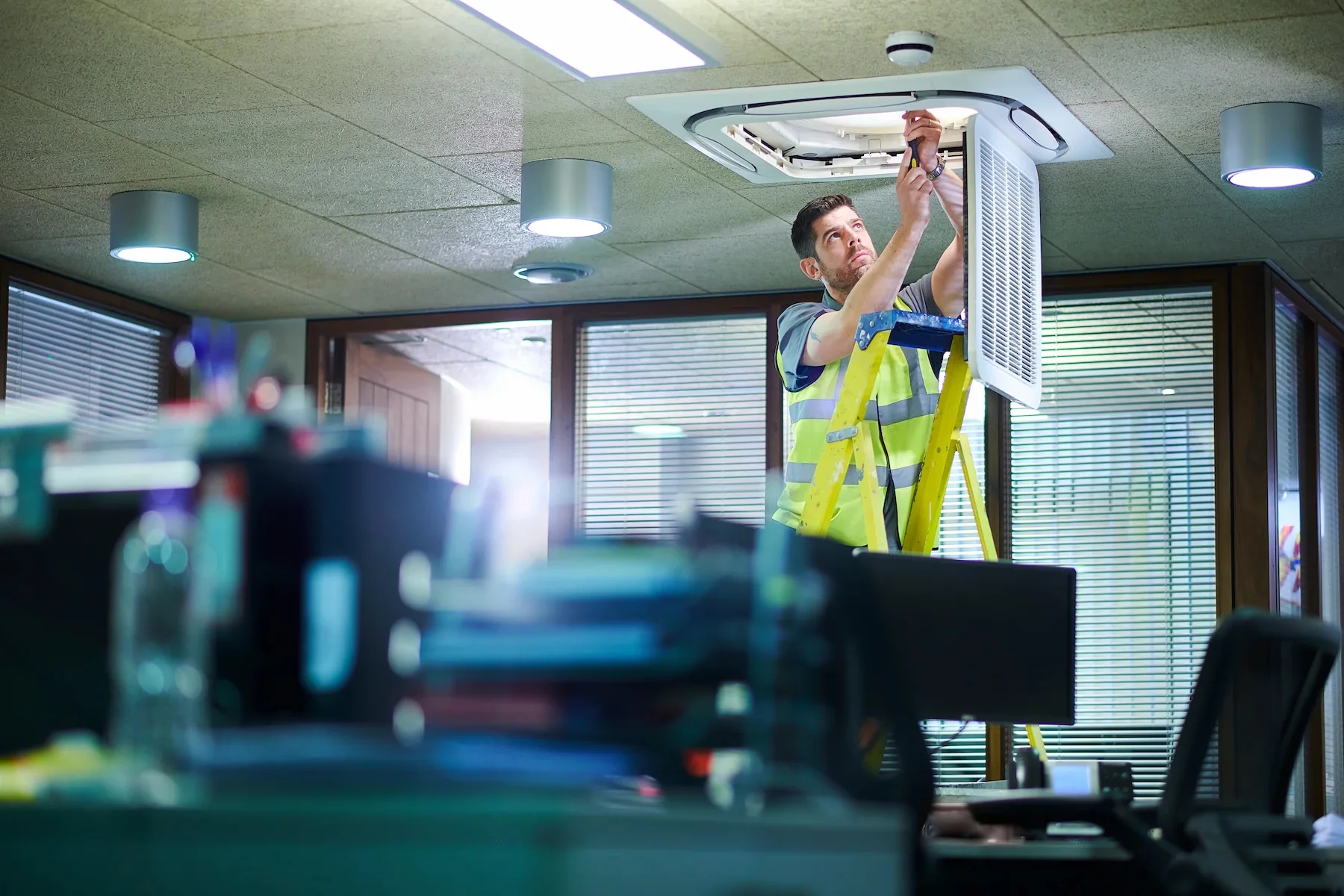 Maintenance technician servicing a ceiling air-conditioning unit