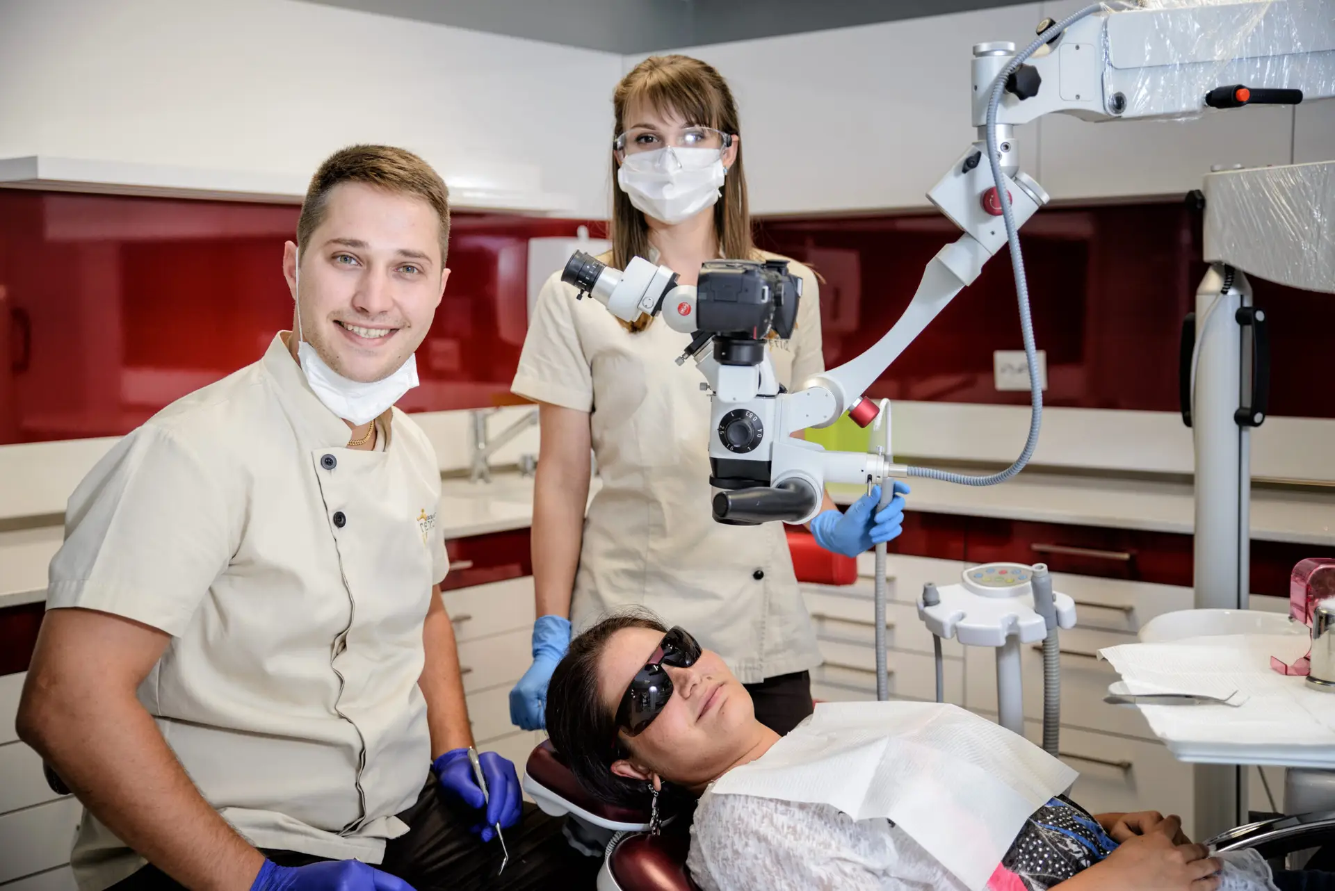 Person sits as two professionals use Karl Kaps Microscopes made in Germany in a bright office with dental