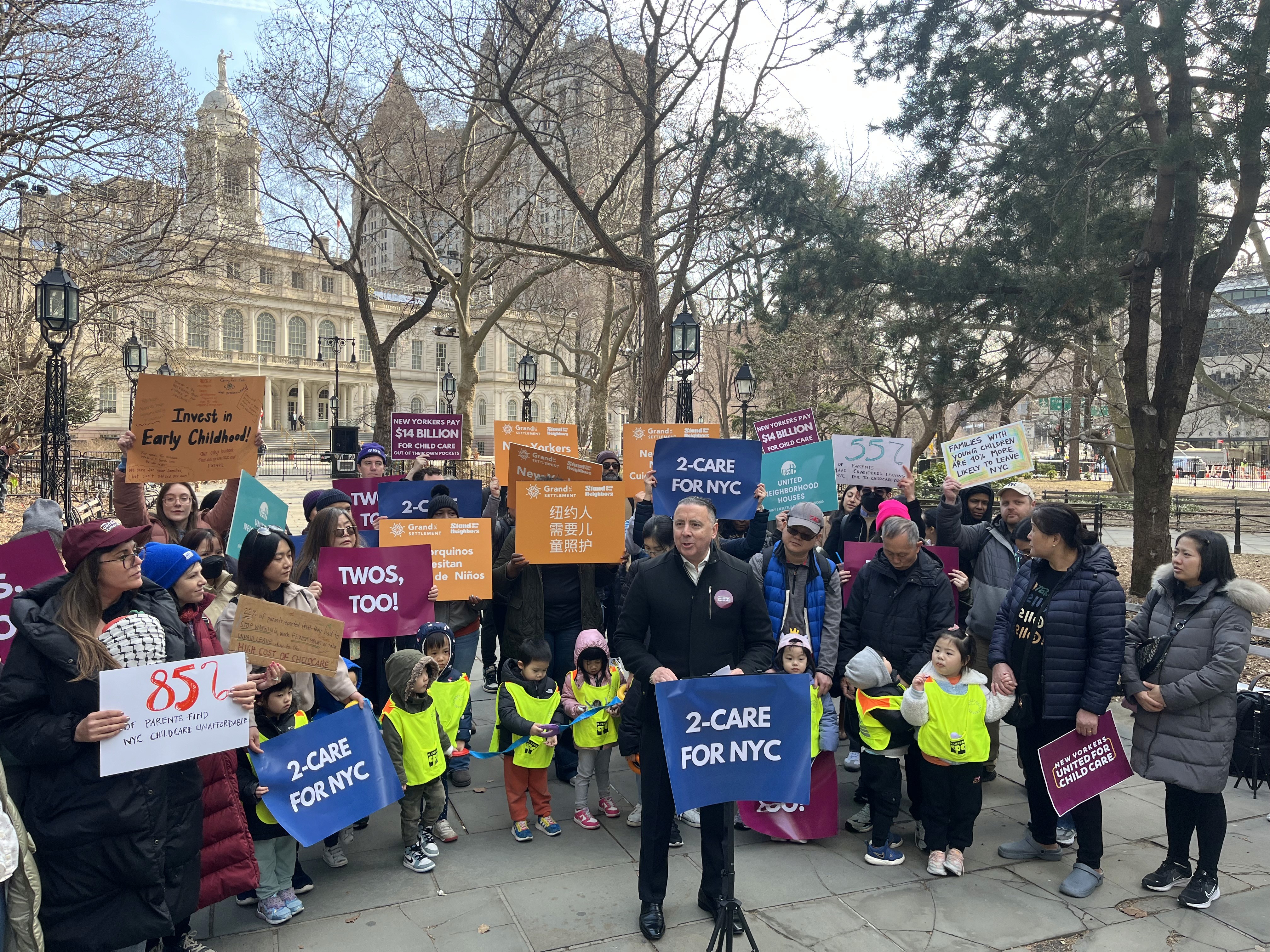 A group of people and children gathered at a rally for preschool funding.
