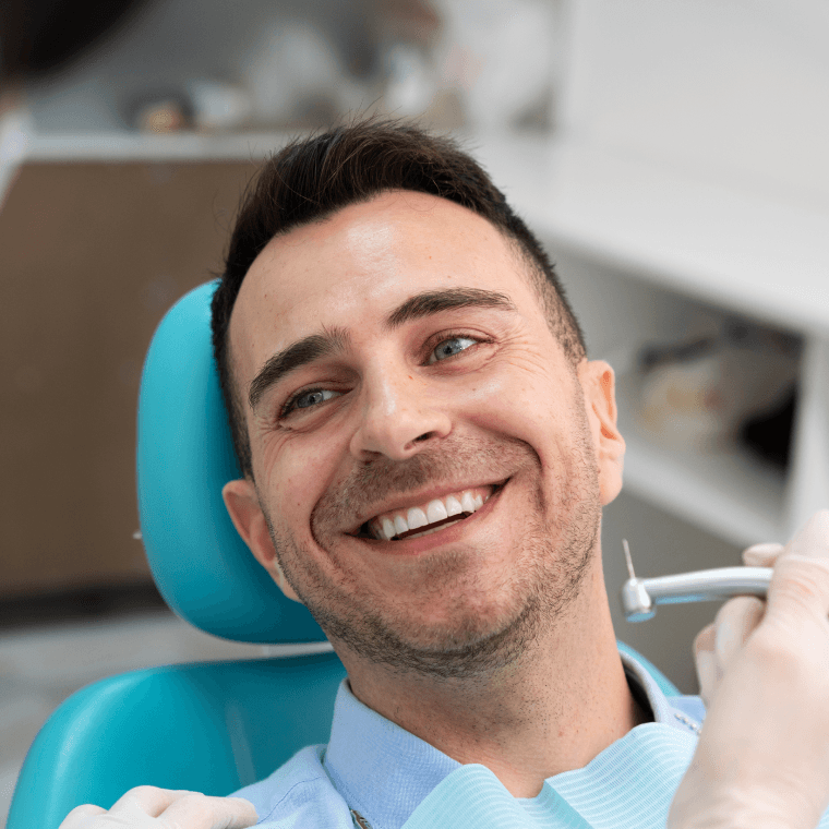 A male patient sitting in a dental chair, smiling and looking satisfied with his dental treatment.