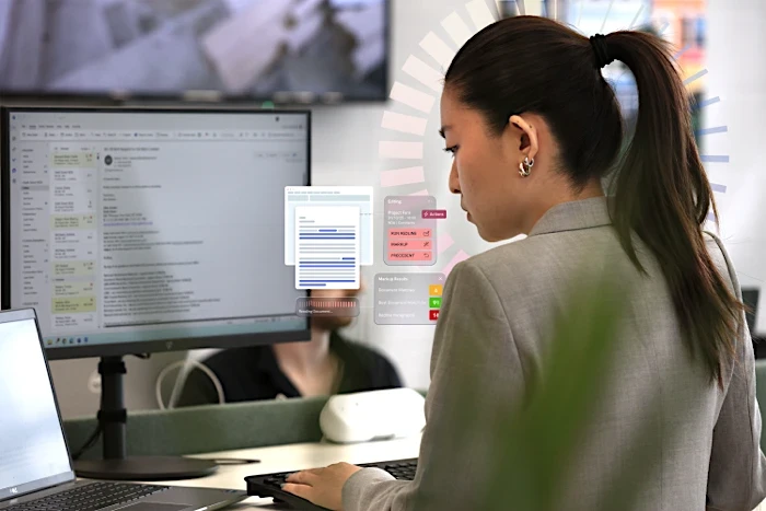 Legal professional reviewing documents on a large monitor, with on-screen highlights representing automated document review and insights.
