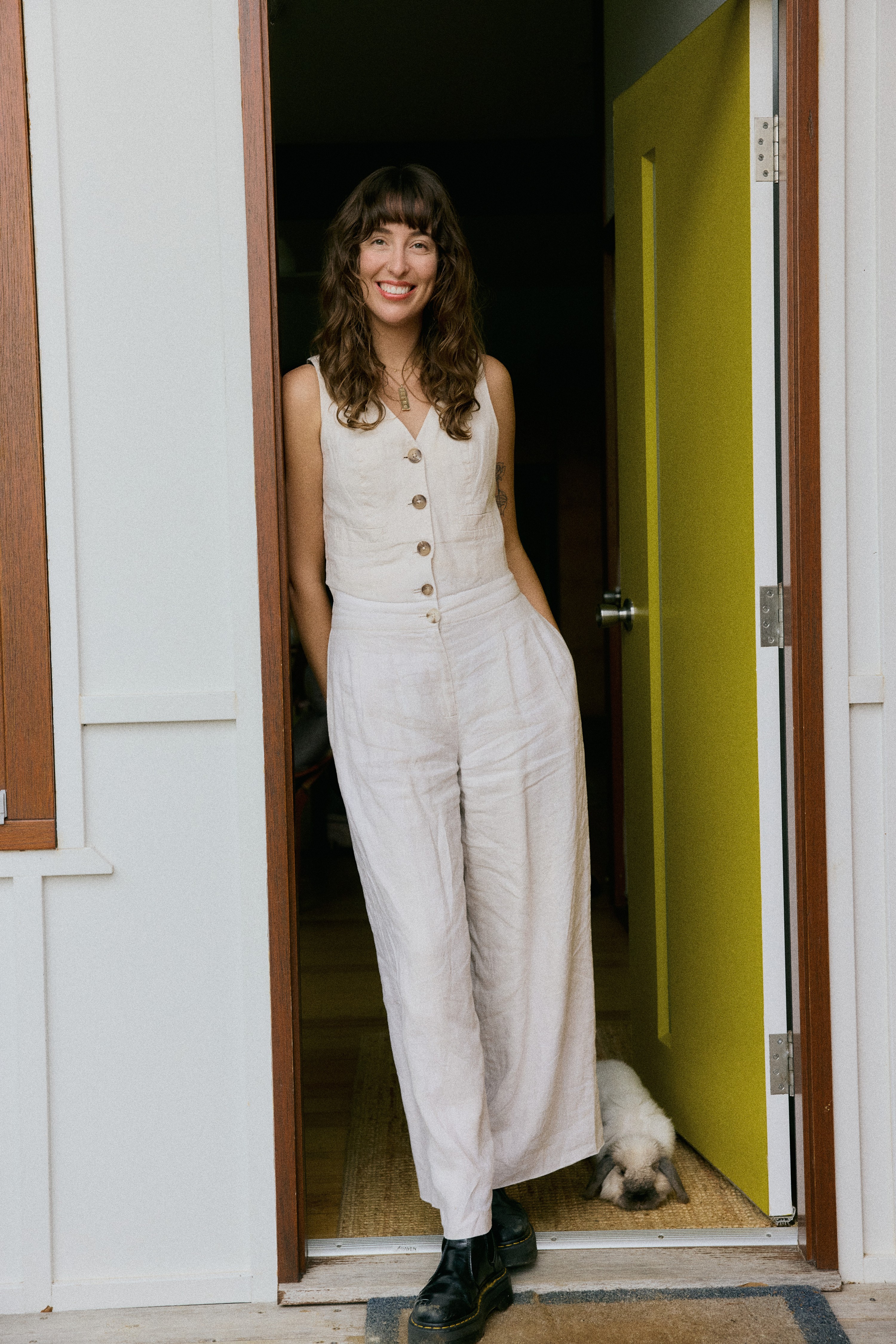 Woman in neutral outfit and a bunny by a doorway.
