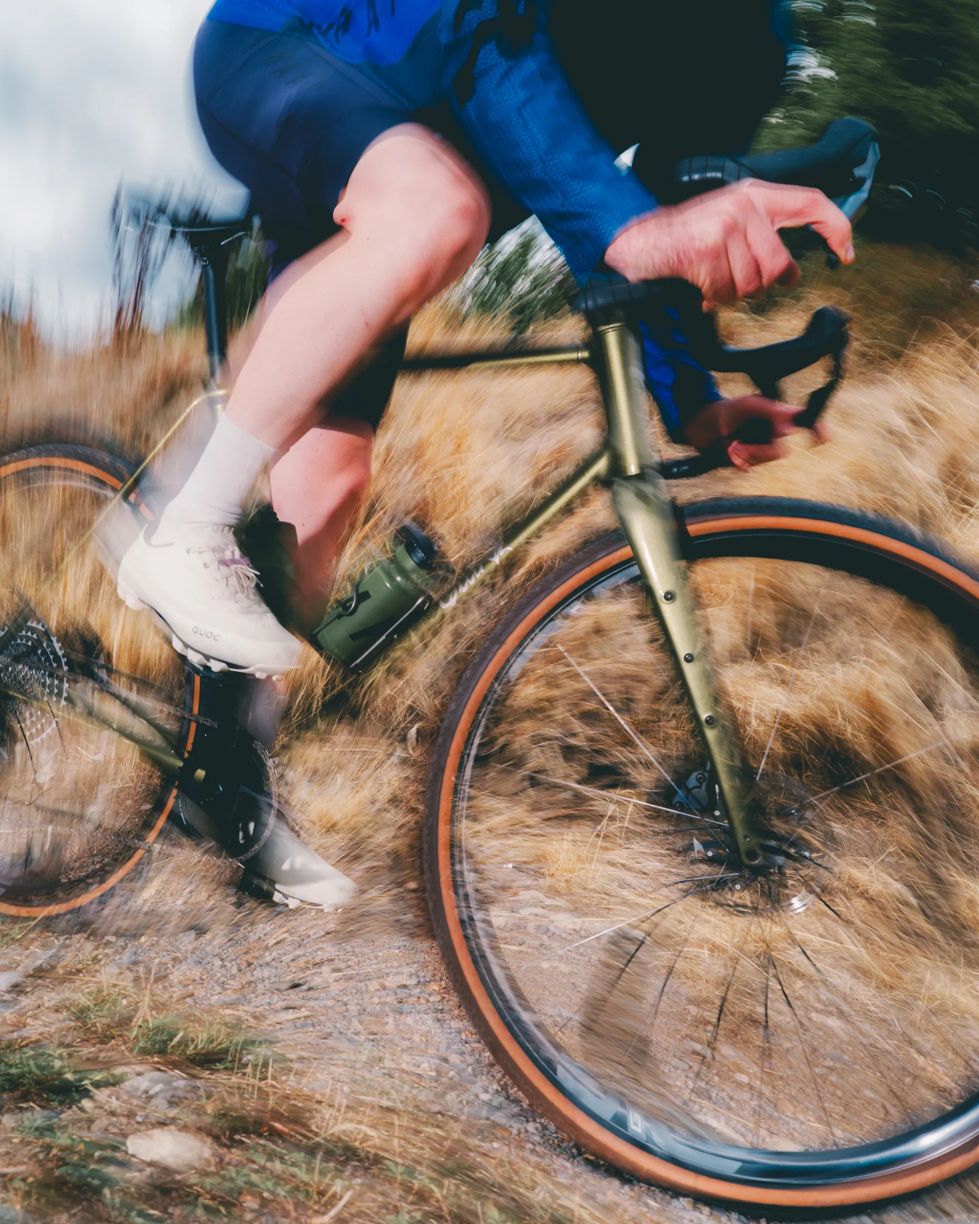 Light blue Quirk Cycles Durmitor road bike in a workshop with dark wheels