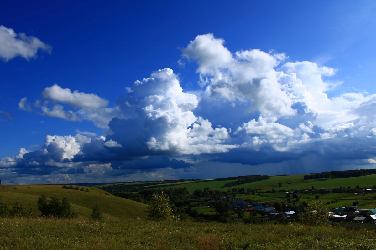 Dramatic clouds over rolling green hills and village