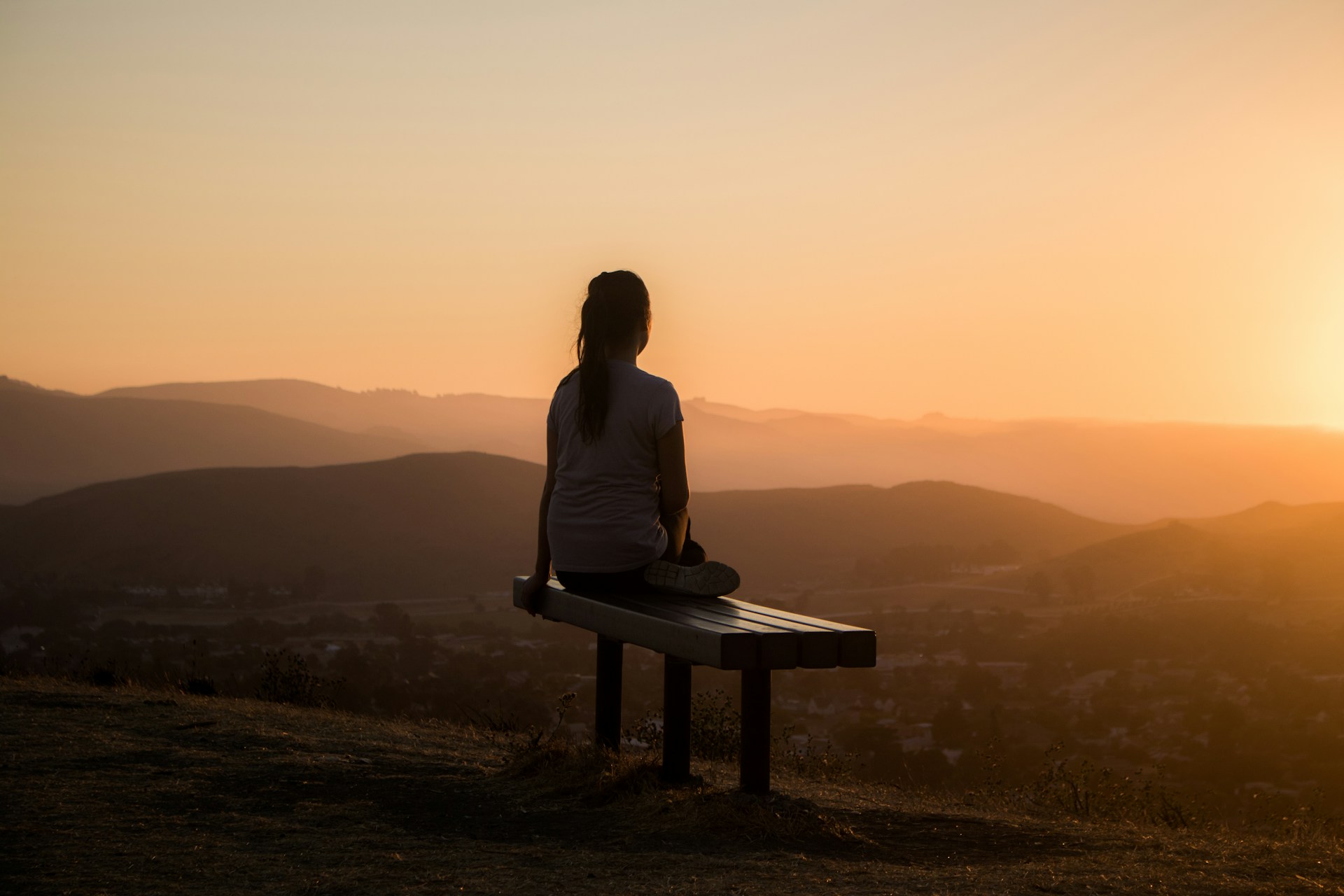 Person sitting on a bench at sunset, reflecting and finding calm balance