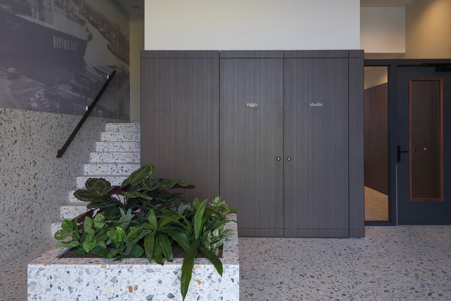Interieur met trap,  plantenbak,  deuren met namen 'ziggo' en 'stedin'