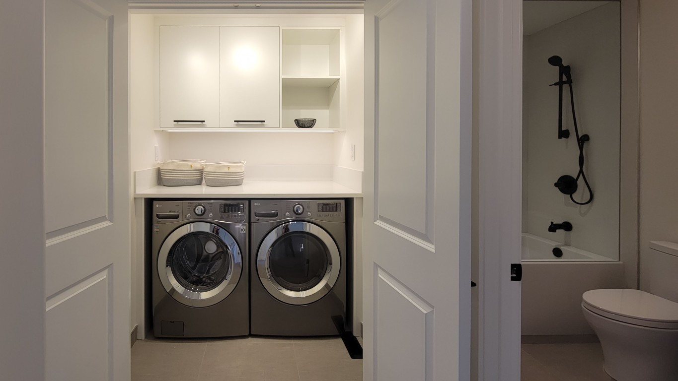 Image of Laundry room interior with washer, dryer, and bathroom featuring modern design and KHD Homes construction.