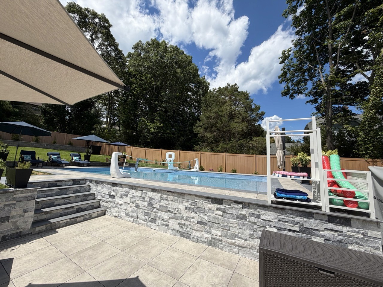 In-ground pool with paver patio at night by CMC Masonry on Long Island