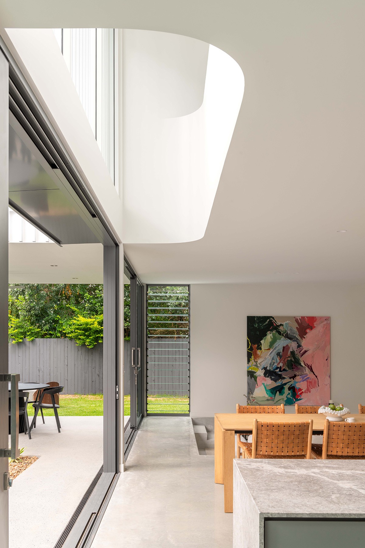 Open-plan kitchen and dining area at The Stables, with full-height glazing, a central skylight, and direct access to the courtyard garden.