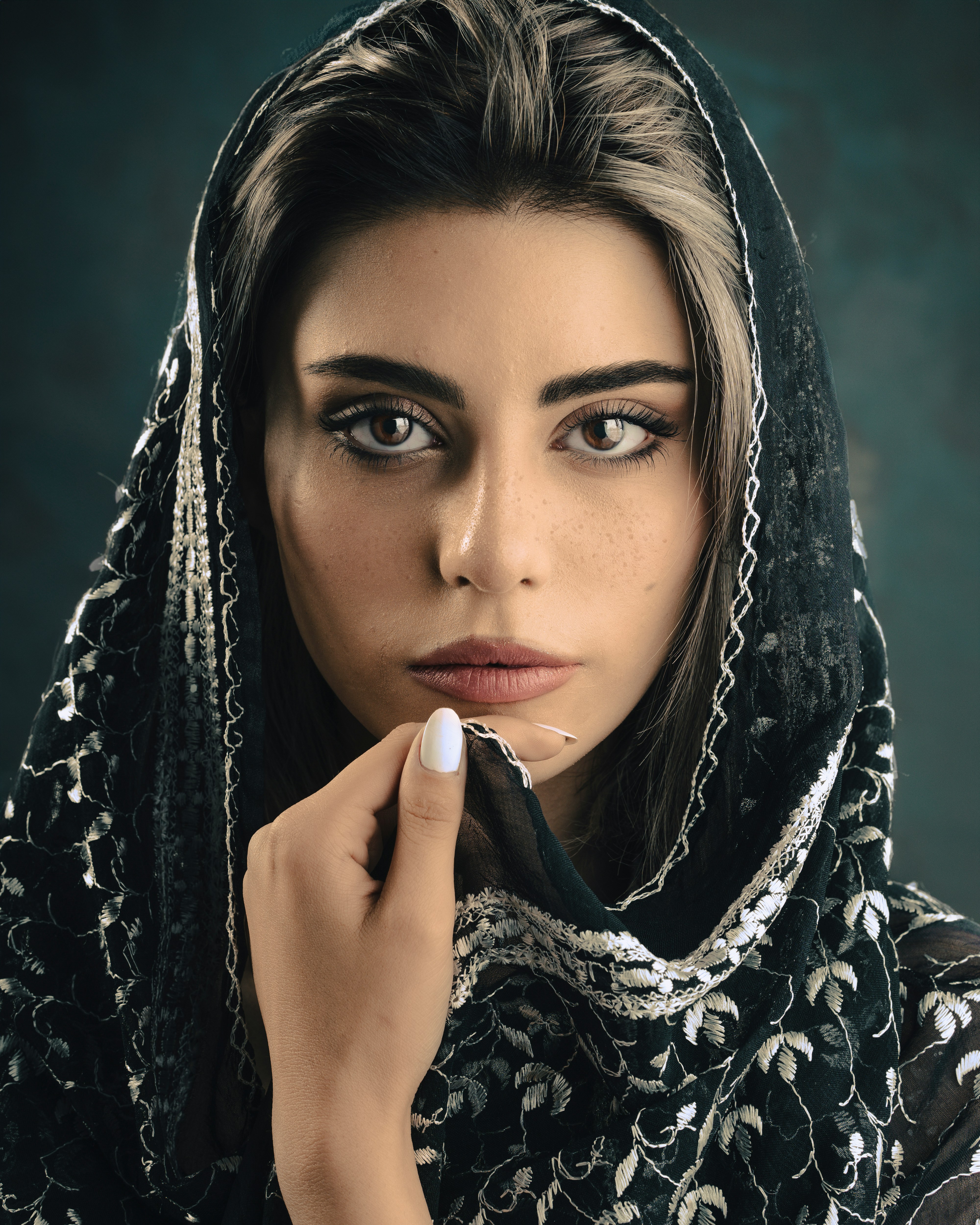 a woman in a black and white shawl holding a cigarette