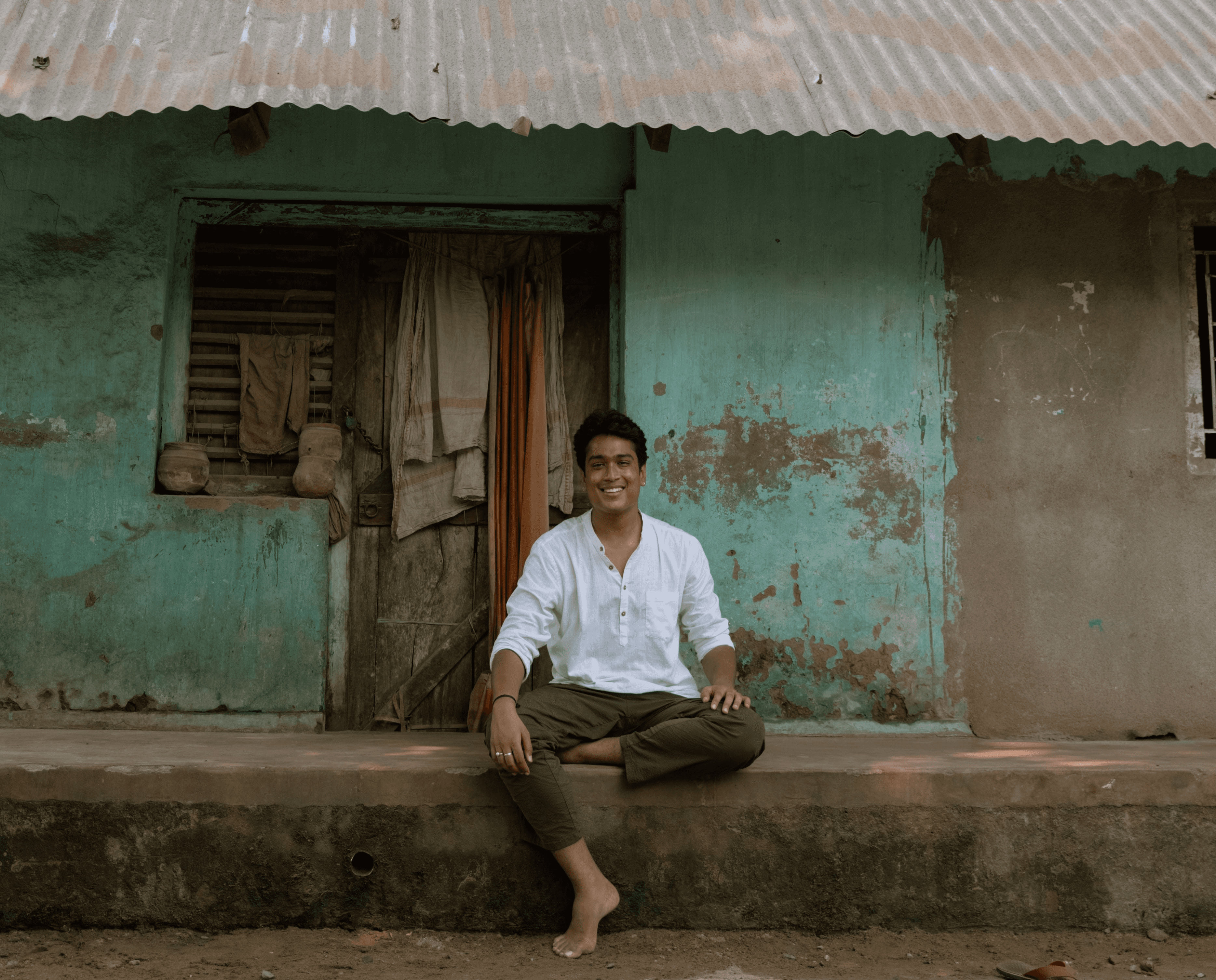 Woman in white yoga outfit sitting cross-legged smiling.