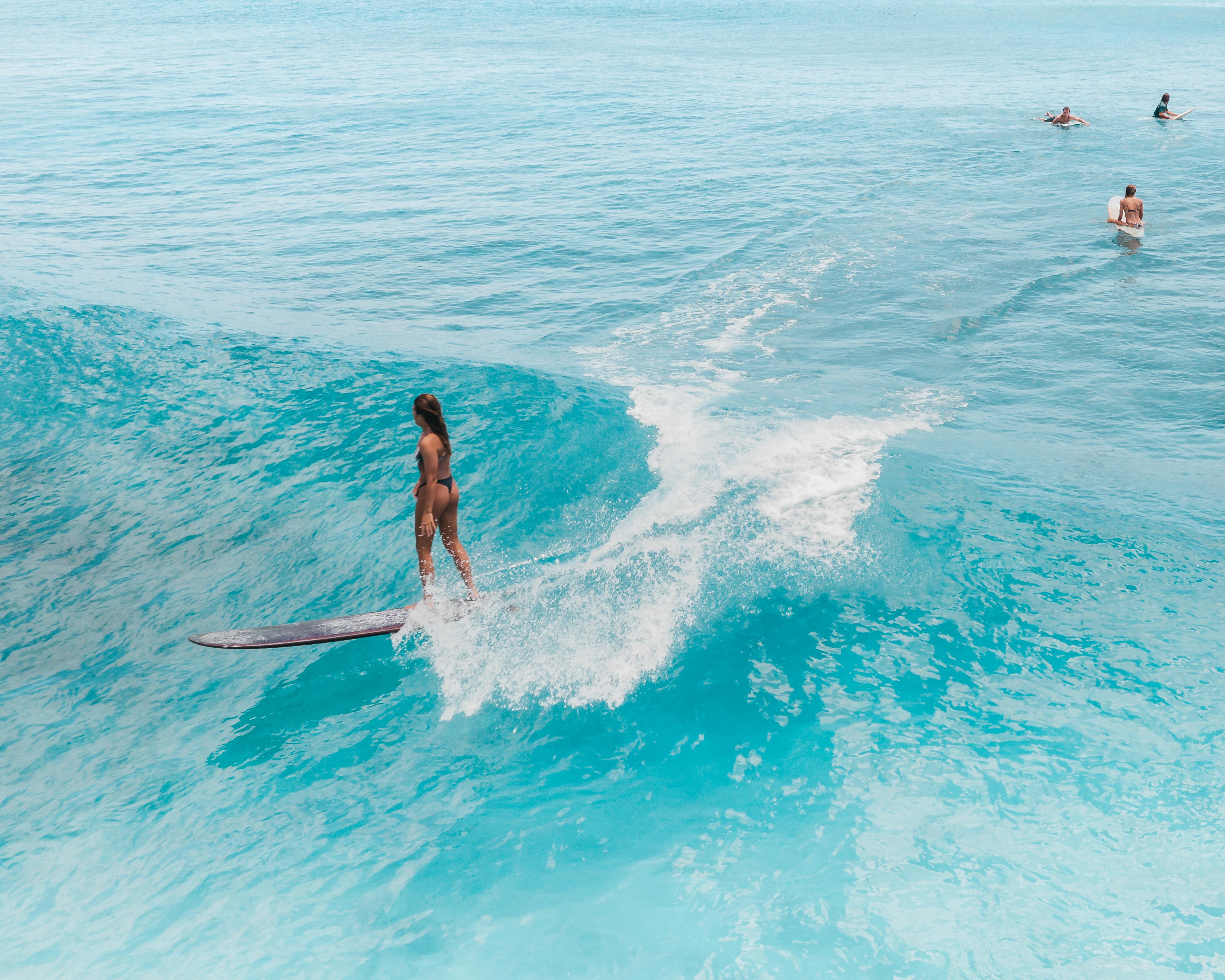 surfer enjoying a relaxed ride on a longboard in calm water, representing body reconnection through movement