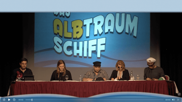 A panel of five individuals seated at a table with a colorful backdrop featuring the text "All Strum to Chiff."