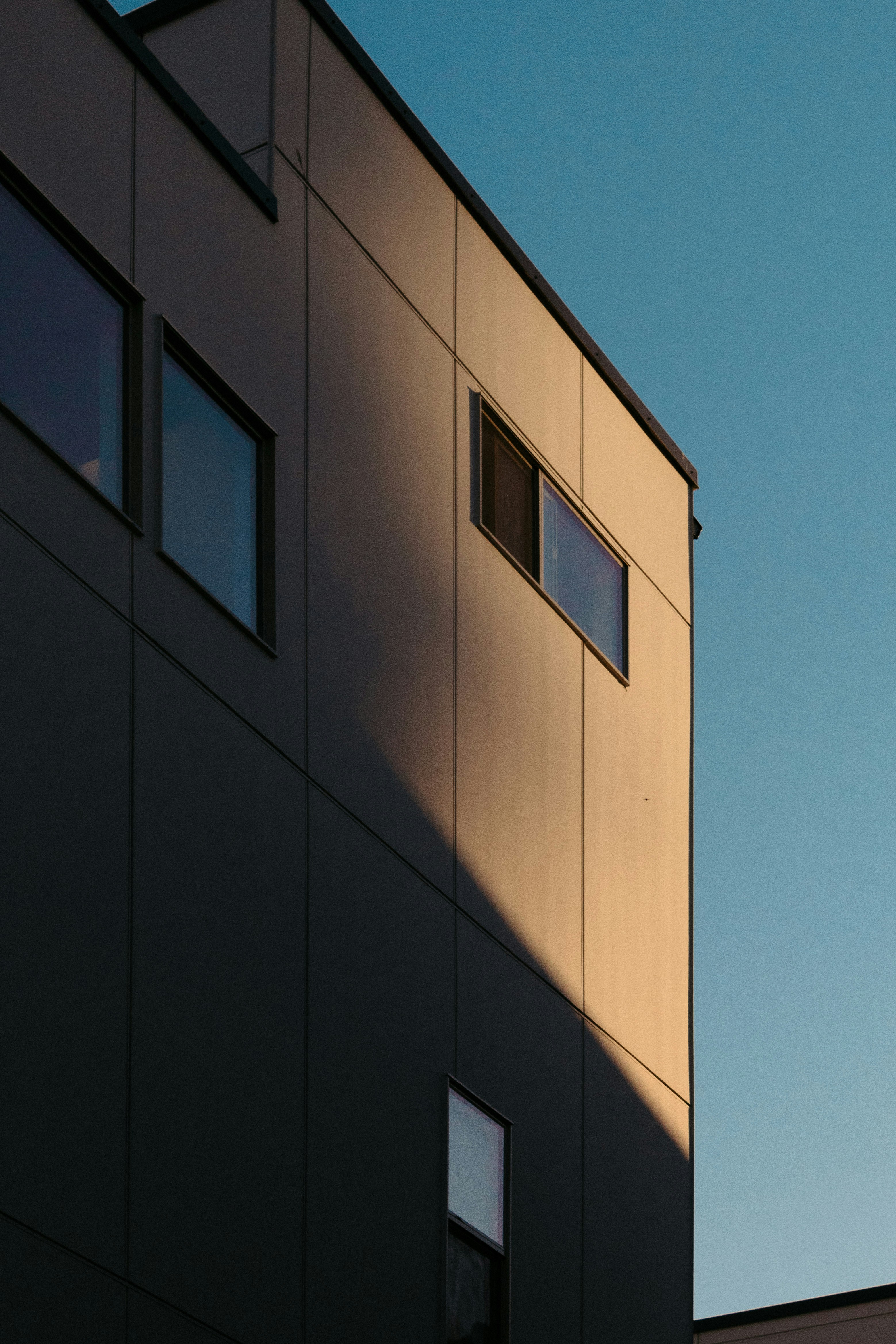 Modern building with sunset shadows and blue sky.