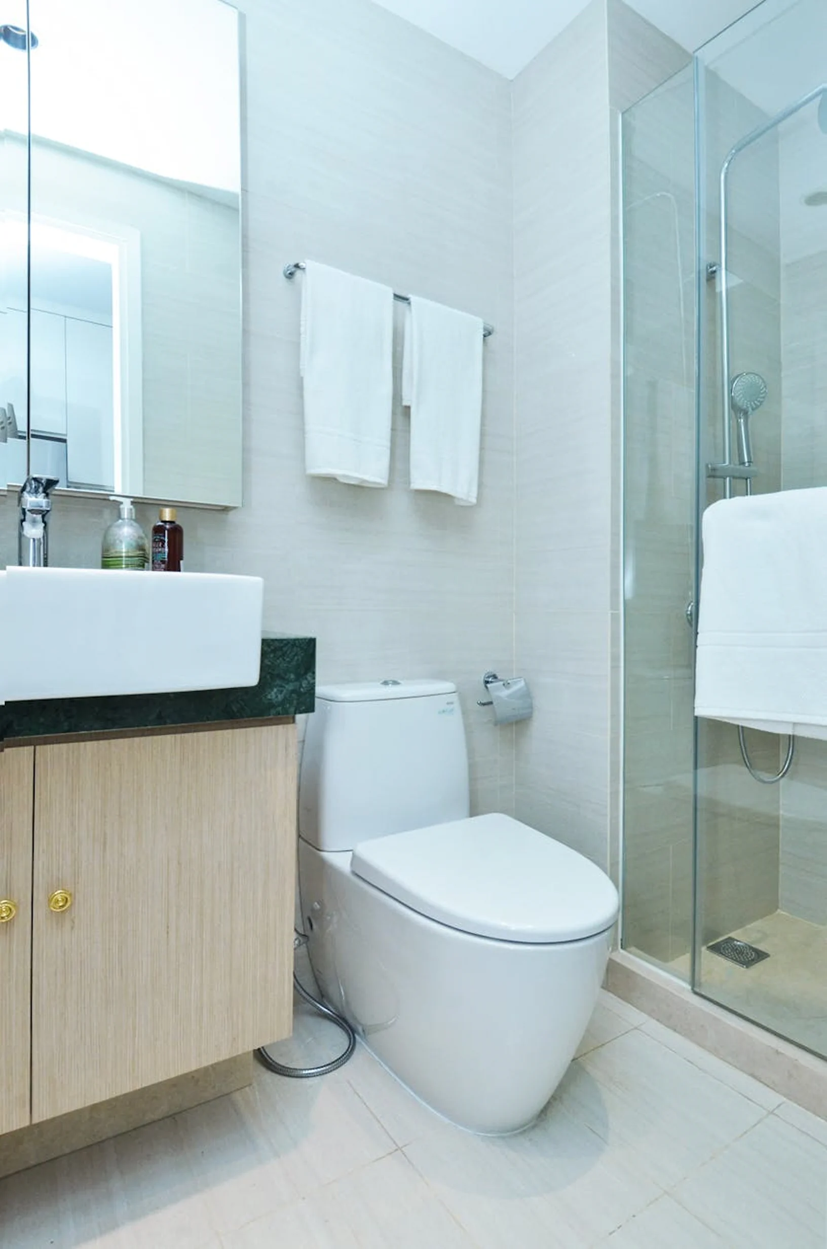Modern bathroom in the family suite with a sink, toilet, glass shower, and clean towels.