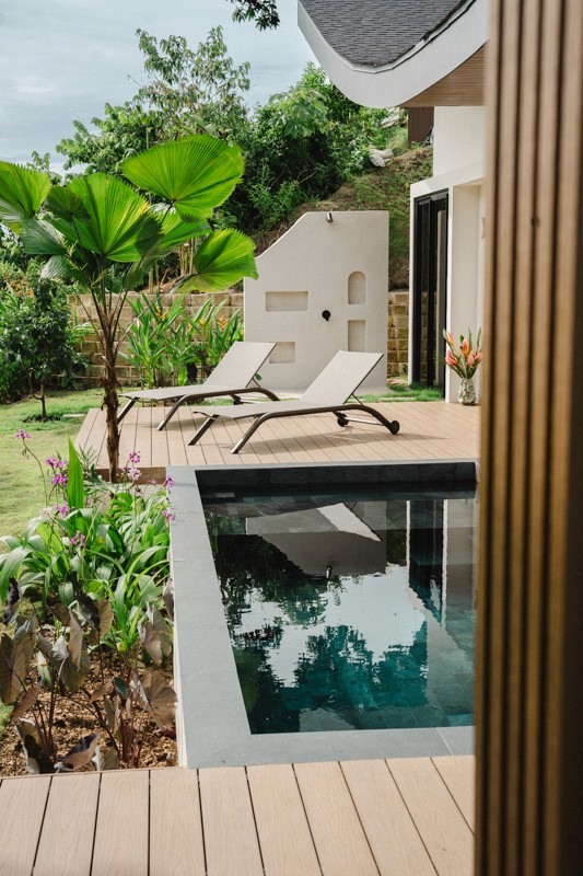 Poolside deck with loungers, tropical plants, and a small private pool beside the contemporary villa.