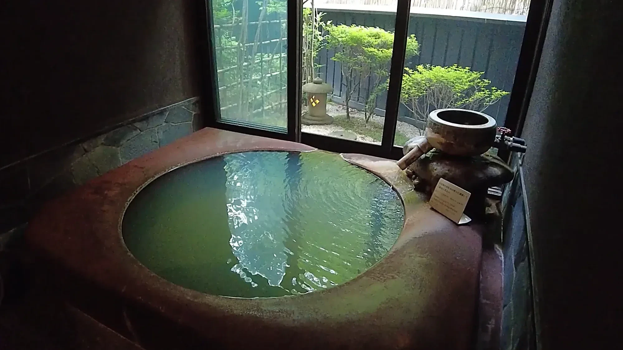 A round copper tub beside a window, forest beyond