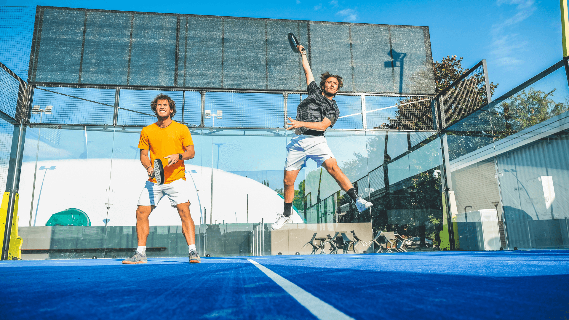 Two men on the court in the middle of a padel game