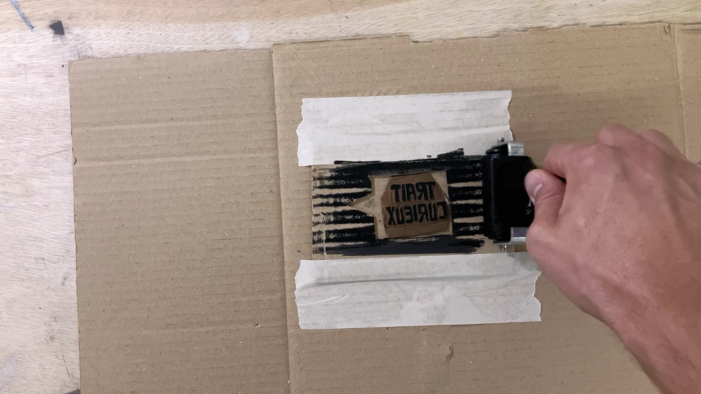 Encrage d'une matrice de linogravure gravée « Trait Curieux » avant tirage sur presse