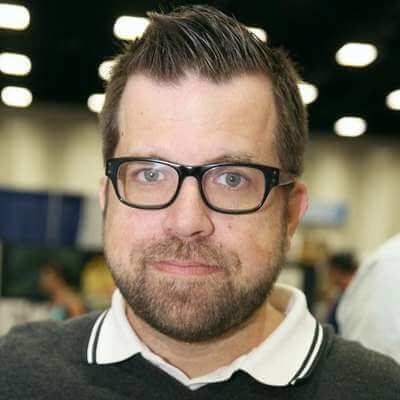 Phil Noto smiling with black glasses and a gray polo shirt with white collar