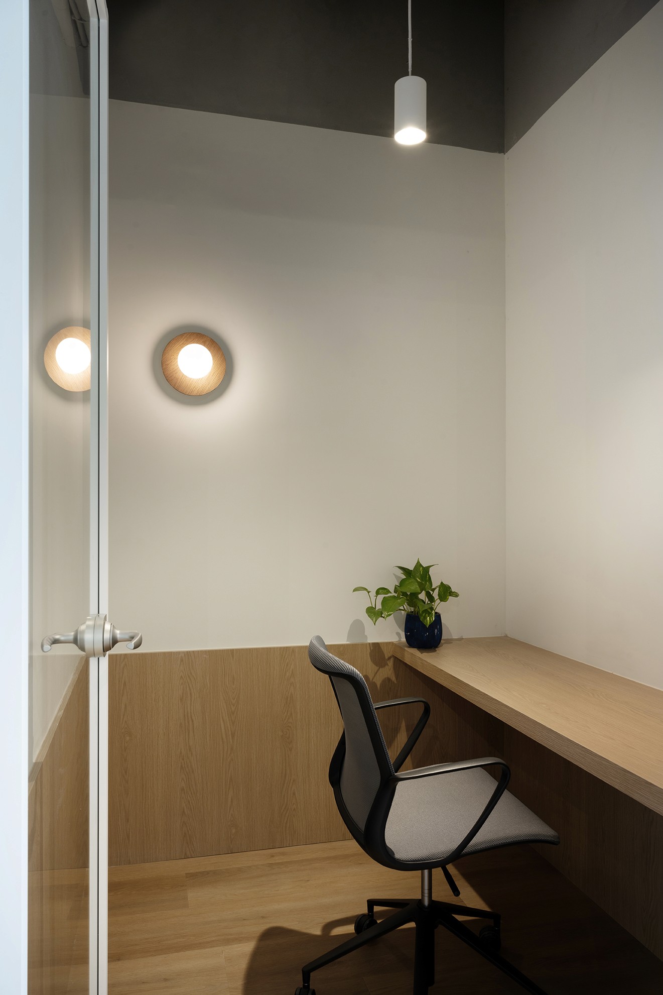 חדר עבודה פרטי (Focus Room): חלל אינטימי לשיחות טלפון וריכוז, המשלב נגרות עץ חמימה וקירות לבנים למראה נקי ושקט