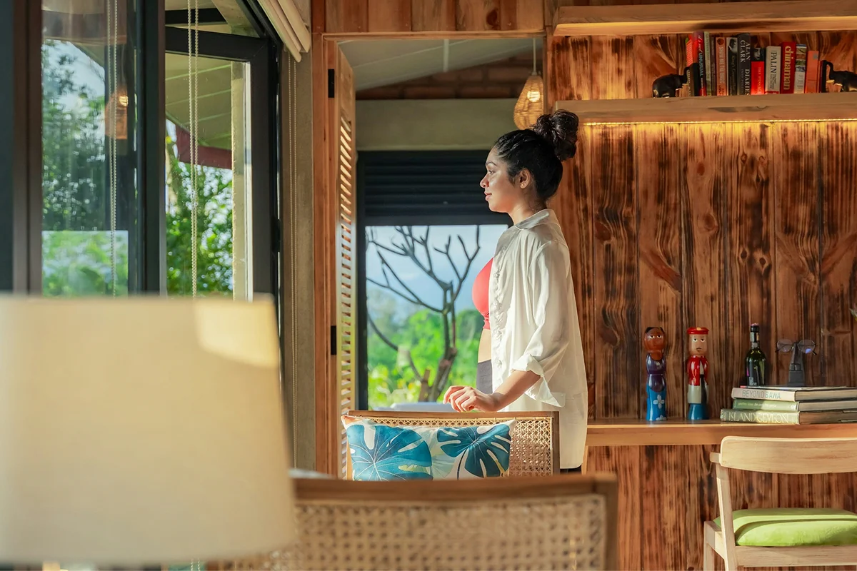 Guest relaxing on a private room balcony overlooking tropical greenery.