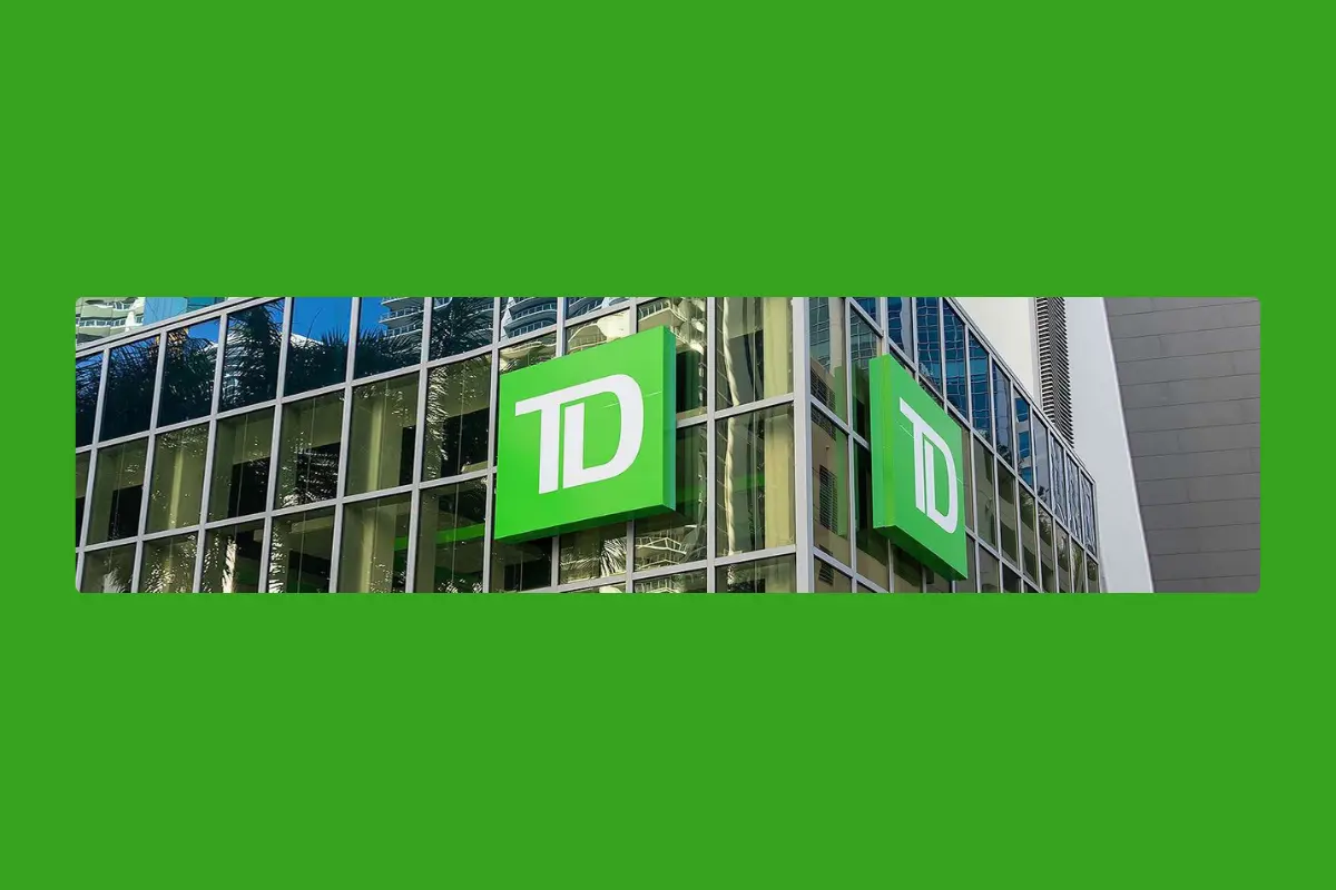 The image shows the exterior of a building with large, reflective glass windows, prominently featuring the green and white logo of a TD Bank, set against the backdrop of a vibrant green sky, indicative of a financial institution in an urban setting, possibly near Bradenton, FL.