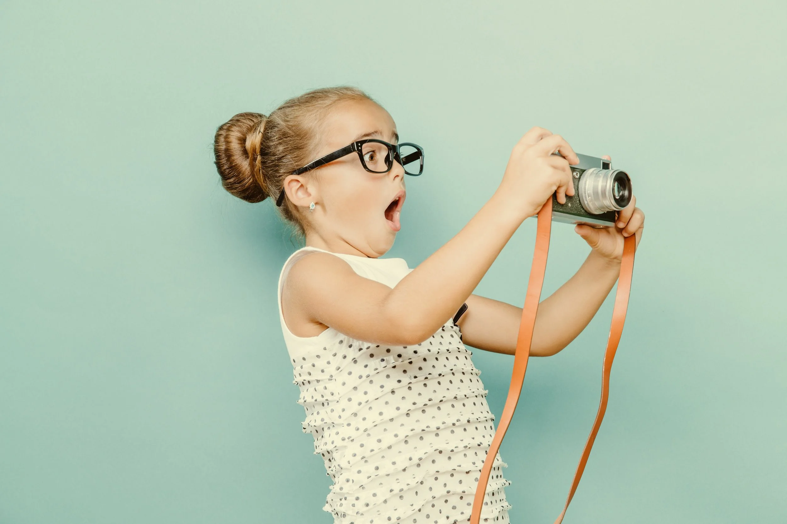 Young girl holding camera looking shocked