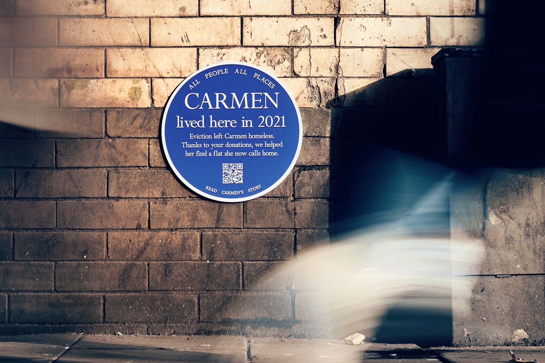 Blue plaque attached to a brick wall that say's Carmen lived here in 2021