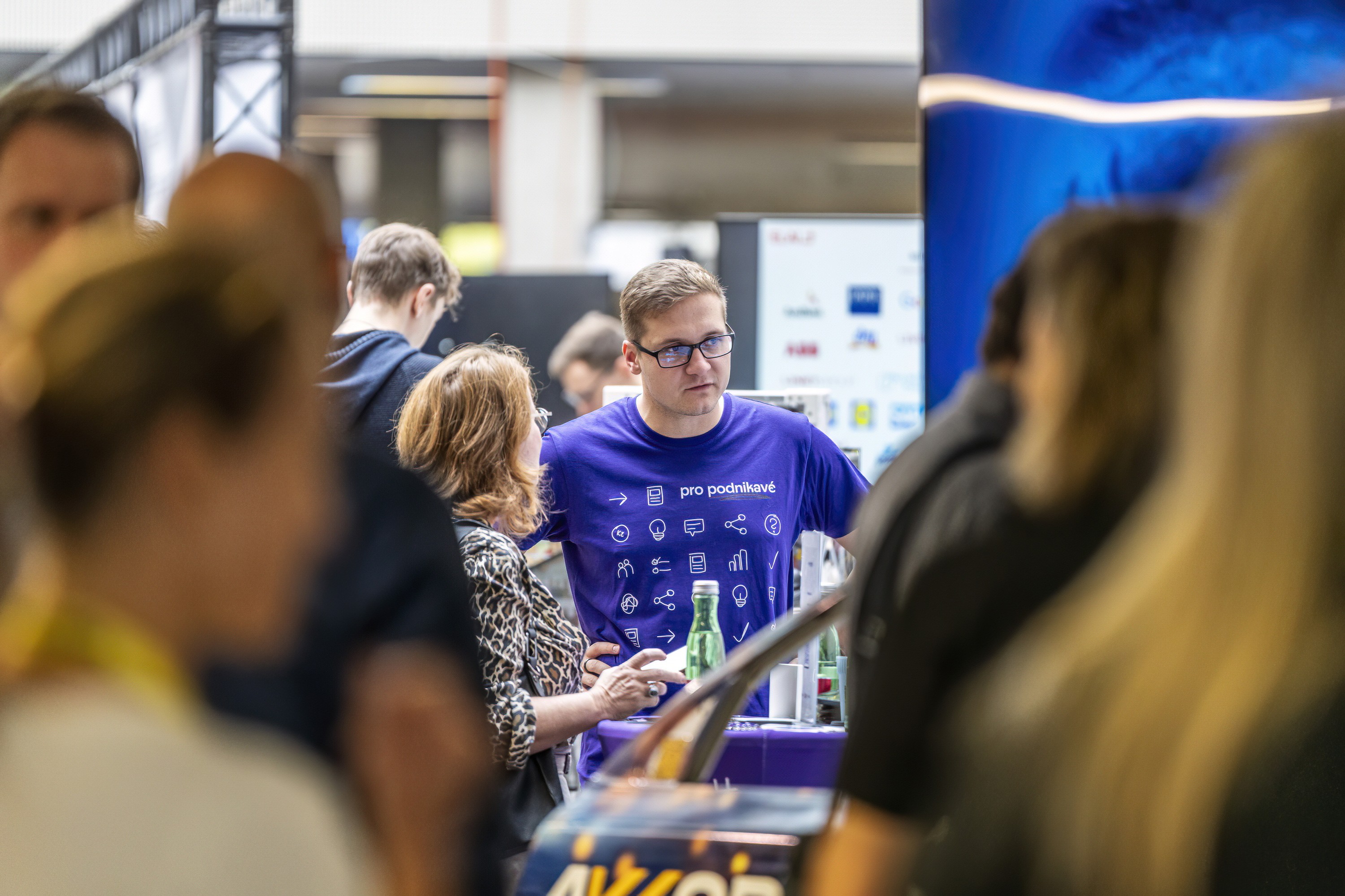 Attendees networking and exploring sponsor booths at a large conference exhibition.