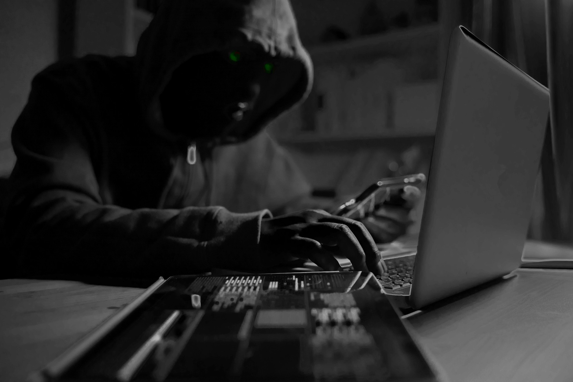 Black and white photo of a hacker stealing data prom a computer.