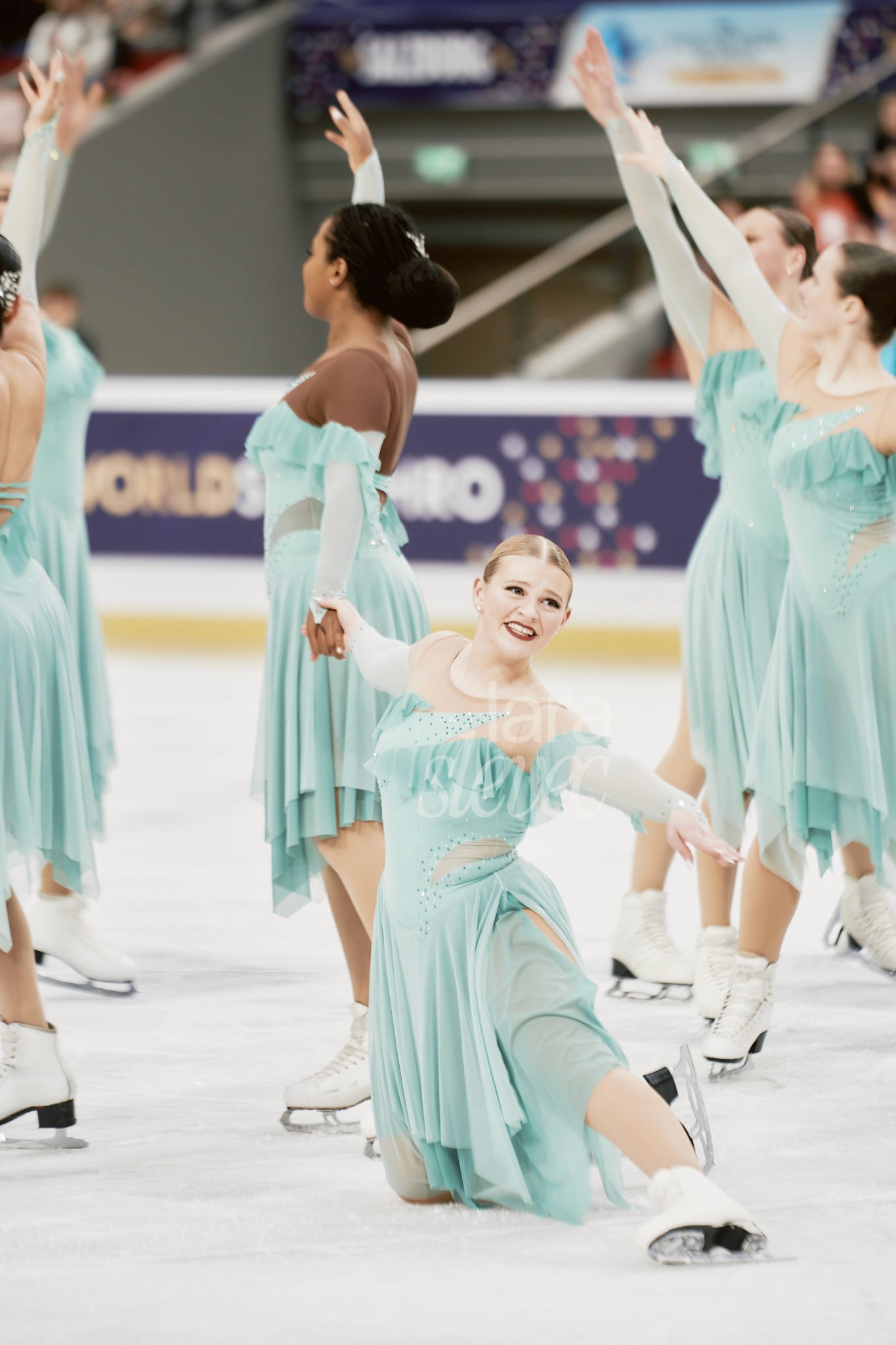 Endpose im Synchroneiskunstlauf. Eine Läuferin kniet mit ausgestrecktem Bein auf dem Eis. Team Cool Dreams. ISU Synchronized Skating Championships 2026 in Salzburg. Fotografiert von Lara Slevec.
