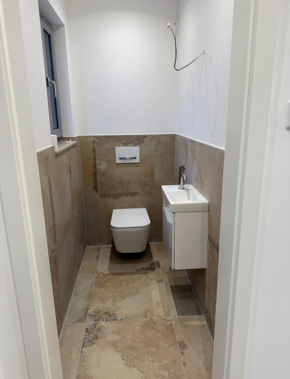 Gäste Badsanierung Nürnberg Gostenhof nachher – modernes Gäste-WC mit wandhängendem WC, Waschtisch und Großformat-Travertin-Fliesen – Bedel Bad