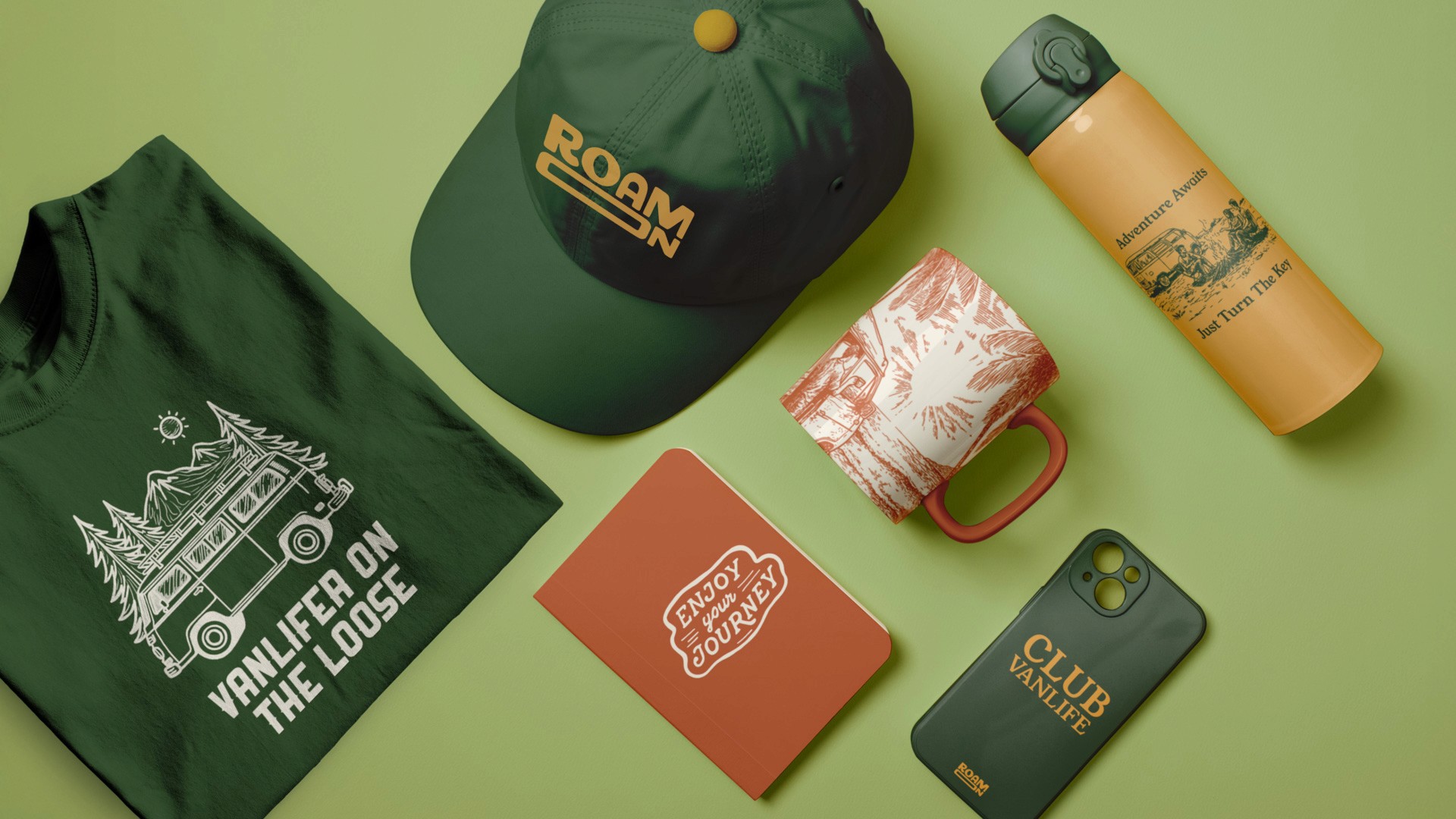 The image shows a flat lay of various items on a light green background. In the top left corner, there is a dark green t-shirt featuring a white graphic of a bus and trees, with the text "VAN LIFER ON THE LOOSE" printed below. In the top center, a dark green baseball cap with "ROAM" written in yellow letters is visible. To the right of the cap is a light orange/tan water bottle with a black cap, labeled "Adventure Awaits: Turn The Knot." In the bottom center, an orange booklet with a white/cream design that says "ENJOY YOUR JOURNEY" is placed. To the right of the booklet is a dark green phone case with "CLUB VAN LIFE" printed in gold.