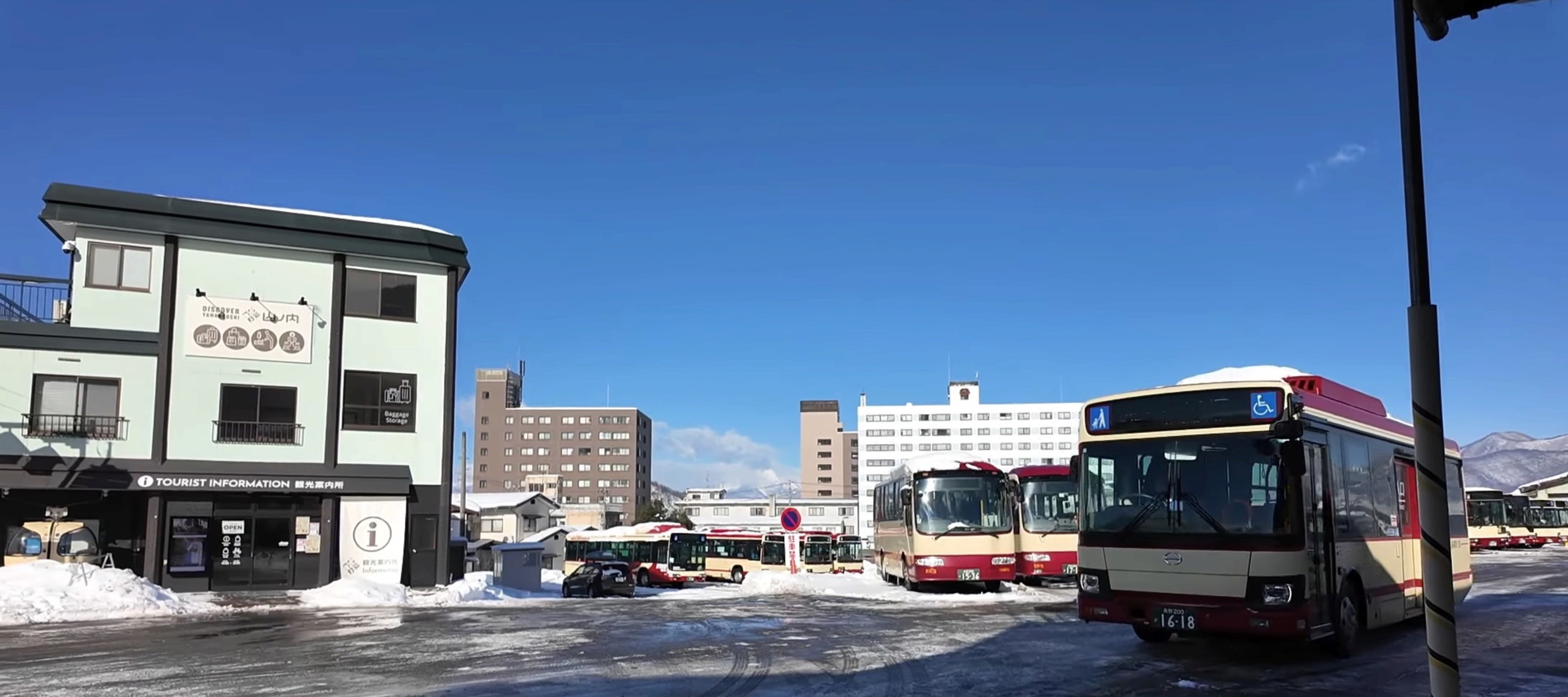 Red and cream local buses at Yudanaka Station bus terminal in winter, the gateway to Jigokudani Monkey Park