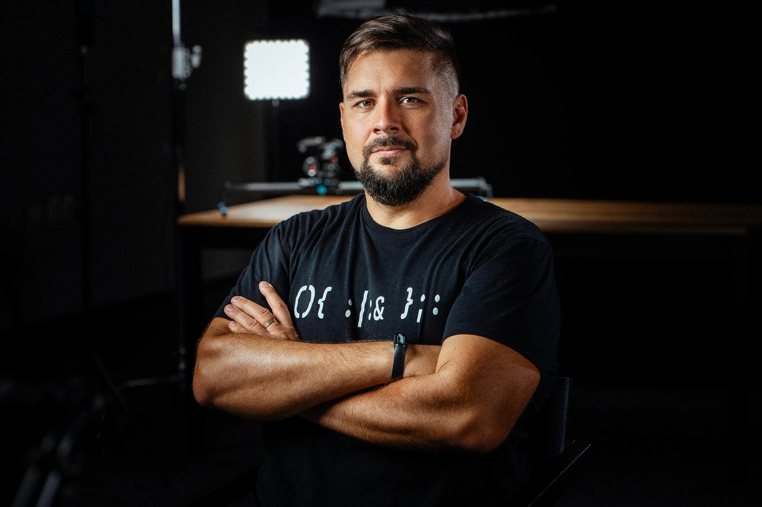 Portrait of a videographer in a studio with a dark, atmospheric background.