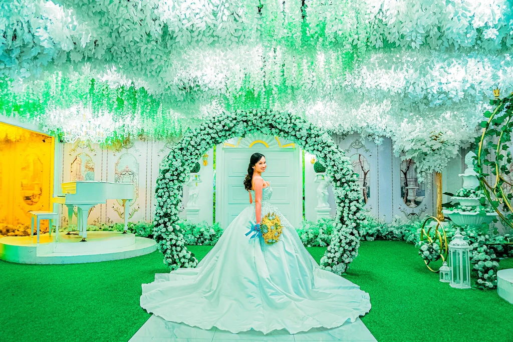 Bride with bouquet beneath the white floral arch at Celestia Hall, Quezon City