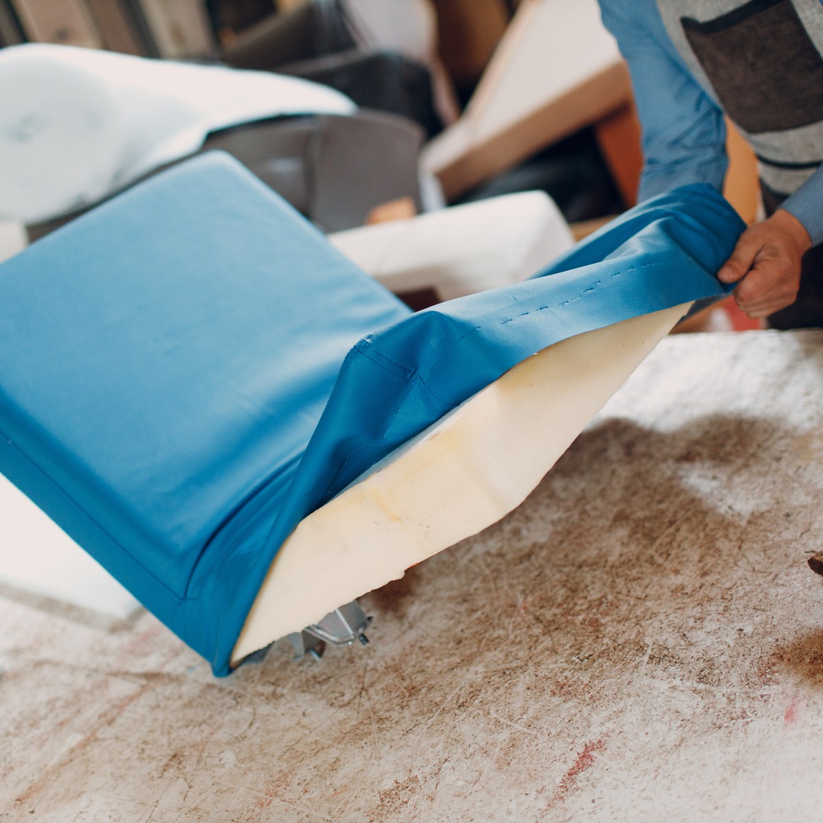 En person som tapetserar en stol med blått tygöverdrag
