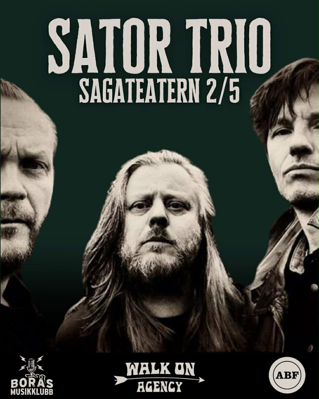 A young person with curly hair smiles at the camera while sitting in front of a laptop against a dark background.