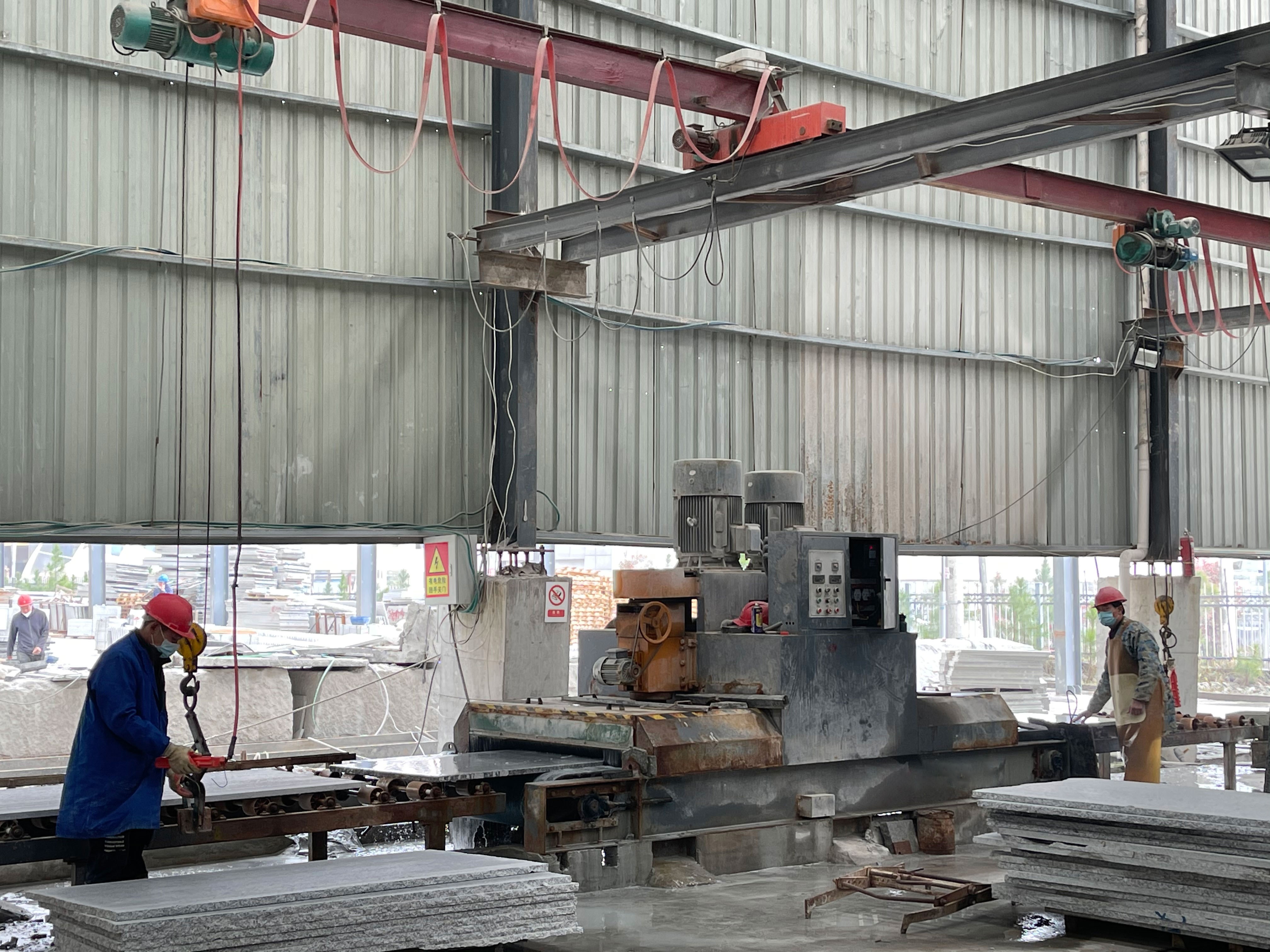 Continuous calibrating machine in operation within an industrial setting, demonstrating its capability to handle large stone slabs with precision and efficiency.