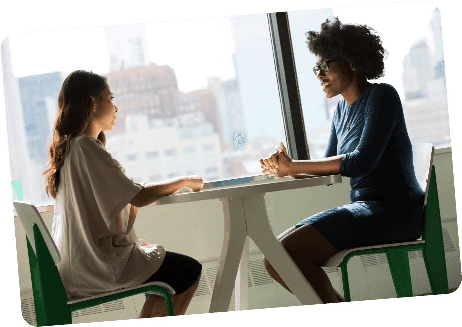 two women interviewing each other at a table in an office setting