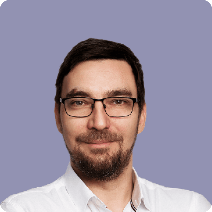 A man with glasses in white shirt in front of a purple background