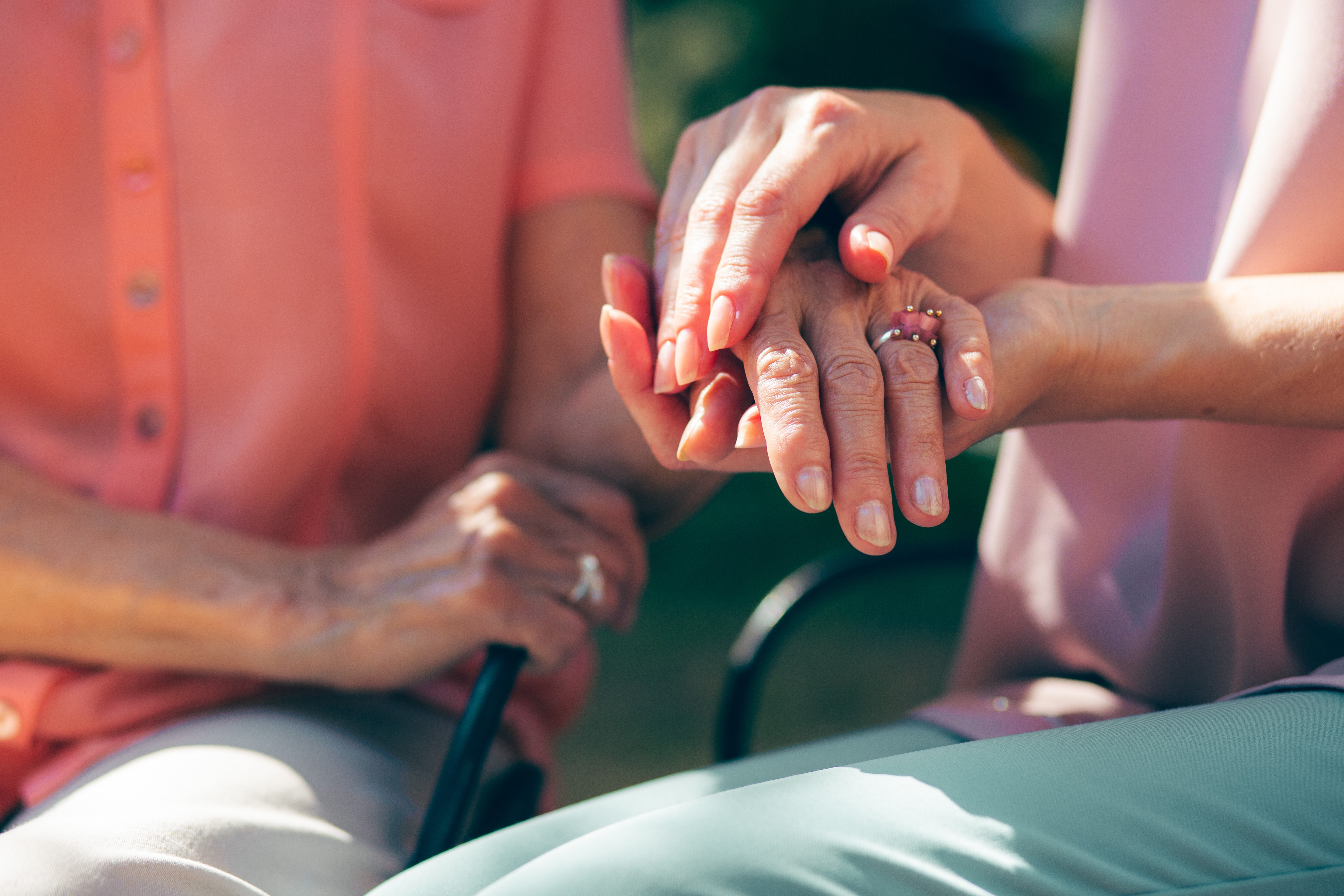 Younger person holding the hands of an elderly person wearing a wedding ring, representing retirement asset division and financial security in Massachusetts divorce proceedings at Lamb & Lamb, P.C.