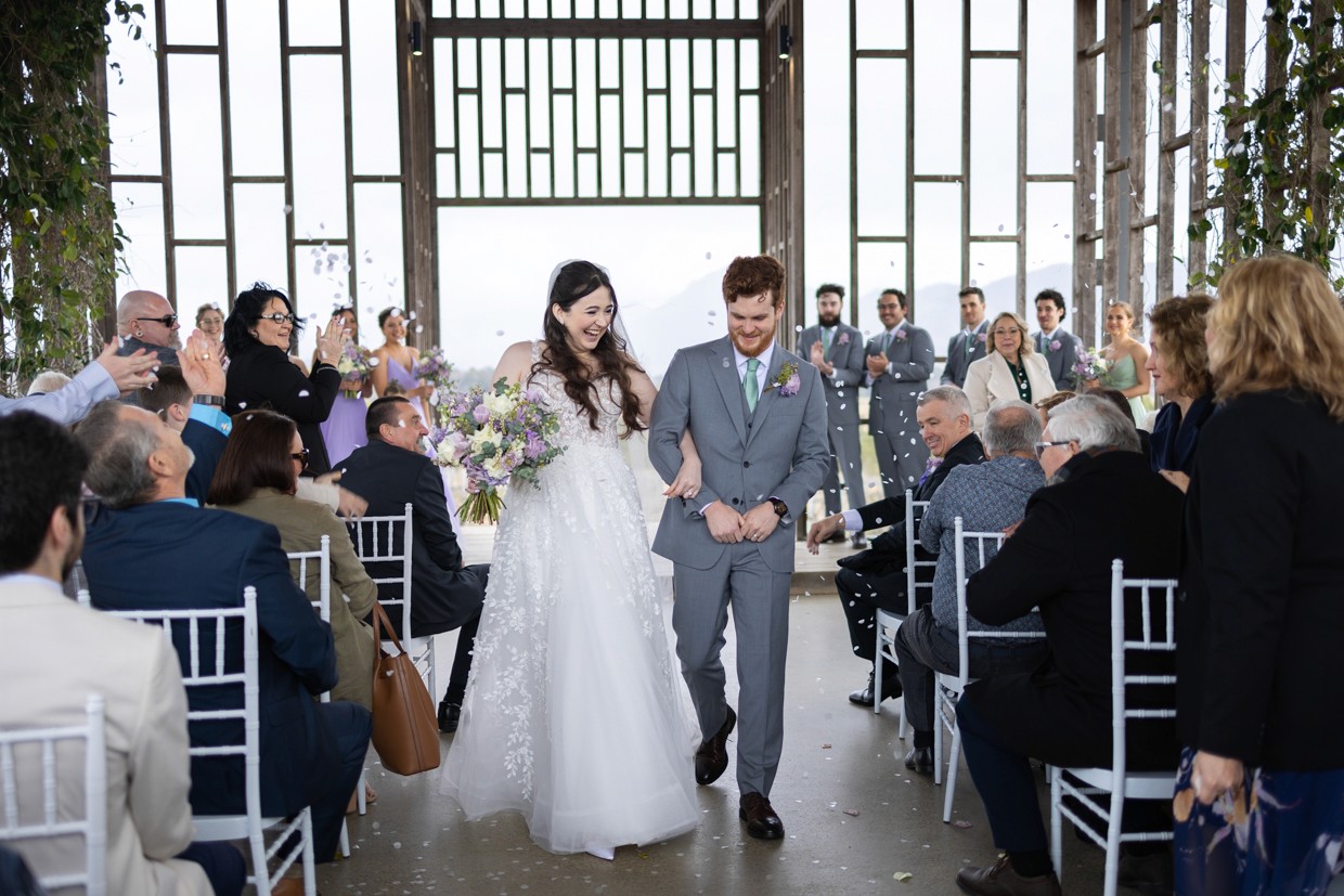 Bride and groom walking down isle with cofetti