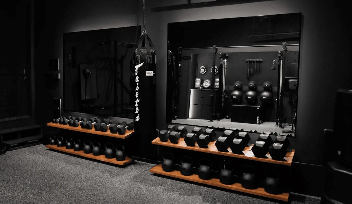Luxury home gym with mirrored walls, dumbbell and kettlebell storage, designed for functional training.