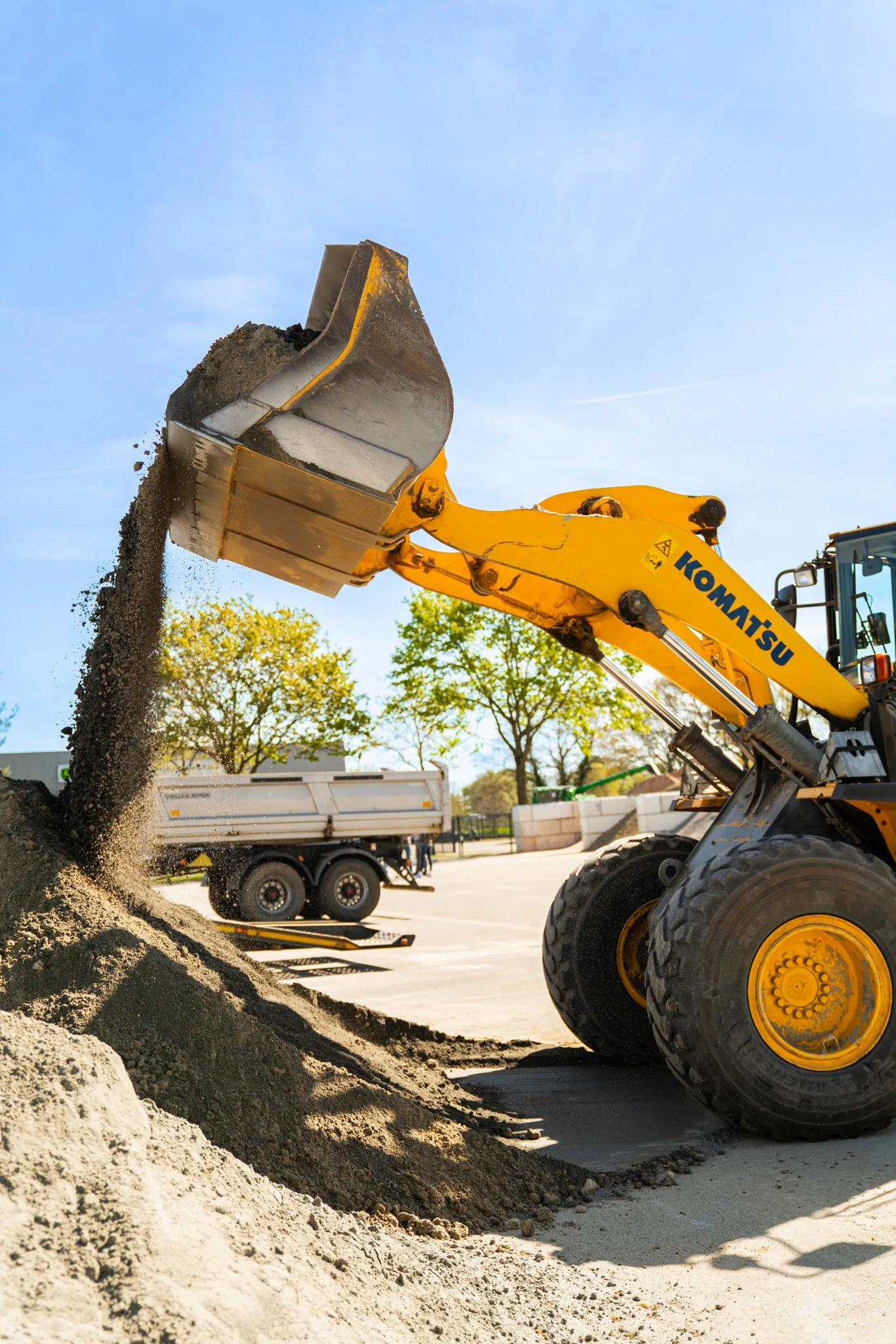 Gelber Komatsu-Radlader schüttet Sand auf einen Haufen