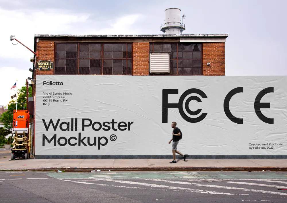 Large wall poster mockup displayed on the side of a brick industrial building, featuring a textured white surface. A person walks past on the sidewalk, with urban details like a crane and utility structures in the background.
