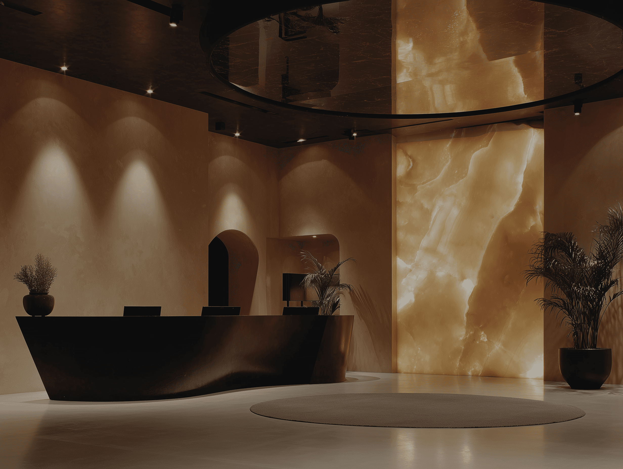 A luxury hotel reception area featuring a dark, curved front desk and a large, glowing onyx wall panel.