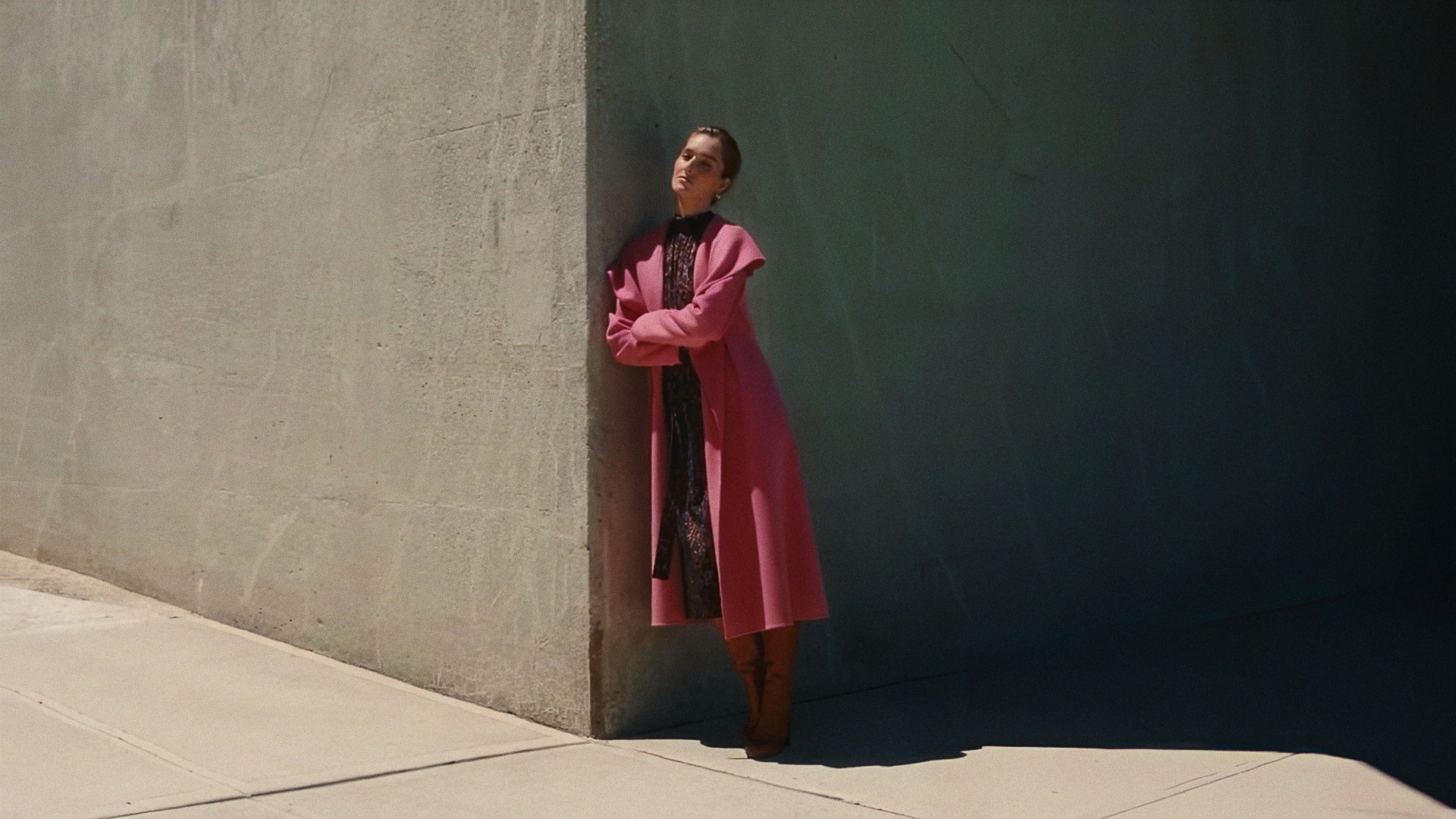A woman in a pink coat standing in the shadow of a concrete wall, Lafayette 148 New York
